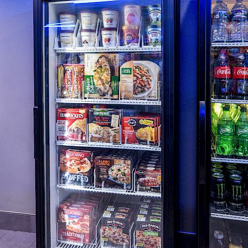 This image shows a refrigerated display with frozen foods like pizzas and meals on the left, and various beverages including sodas and energy drinks on the right.