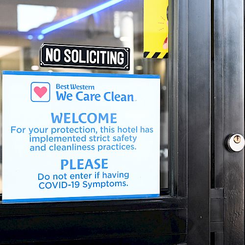 A door sign from Best Western advising of strict safety measures and requesting not to enter if experiencing COVID-19 symptoms.