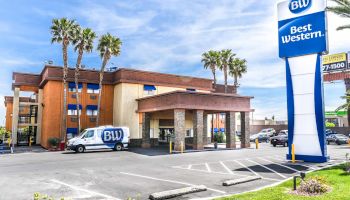 An image of a Best Western hotel with palm trees, a van with the BW logo, a clear blue sky, and a Best Western sign in the foreground ends the sentence.