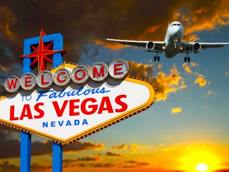 Image of the Welcome to Fabulous Las Vegas, Nevada sign with an approaching airplane in the background against a sunset sky.